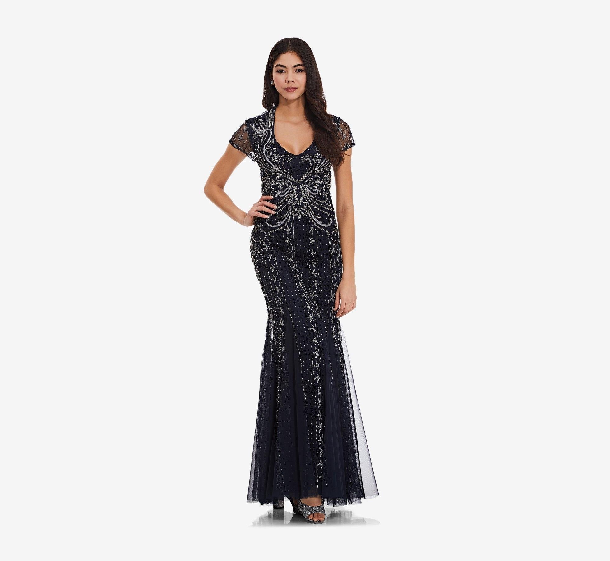 This stunning gown features a V-neckline short translucent sleeves and an intricate pearl corsage. Long A-line flowing soft skirt with pearl detail and is made of mesh embroidered with pearls while the back showcases a cut style. Perfect for any special occasion.<br data-mce-fragment="1"><br data-mce-fragment="1"><br data-mce-fragment="1">Fabric : Mesh<br data-mce-fragment="1"><br data-mce-fragment="1">Zipper Back<br data-mce-fragment="1"><br data-mce-fragment="1">Length : Full Length<br data-mce-fragment="1"><br data-mce-fragment="1">Sleeve Style : Short Sleeve<br data-mce-fragment="1"><br data-mce-fragment="1">Color : Midnight<br data-mce-fragment="1"><br data-mce-fragment="1">Sizes : 10, 12, 14, 16, 18<br data-mce-fragment="1"><br data-mce-fragment="1">Fully Lined<br data-mce-fragment="1"><br data-mce-fragment="1">Occasion : Formal, Evening Party, Mother of the Bride, Mother of the Groom, Church, Wedding Guest